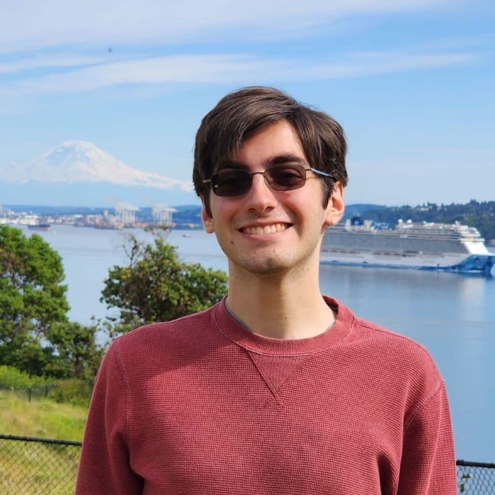 Antonio Ballesteros smiling in front of the Puget Sound with Mount Rainier in the background.