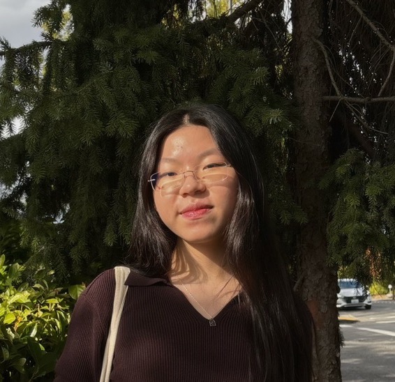 Emma Huang smiling next to a tree.