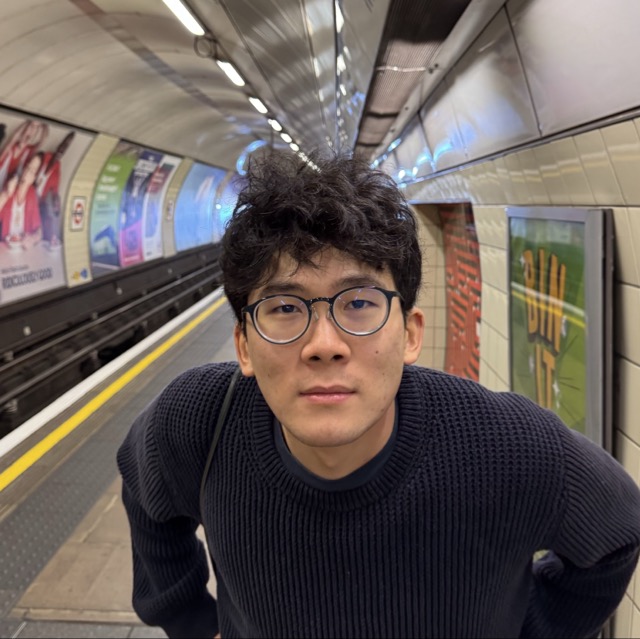 Eric Han standing on a subway platform looking at the camera accusatively.