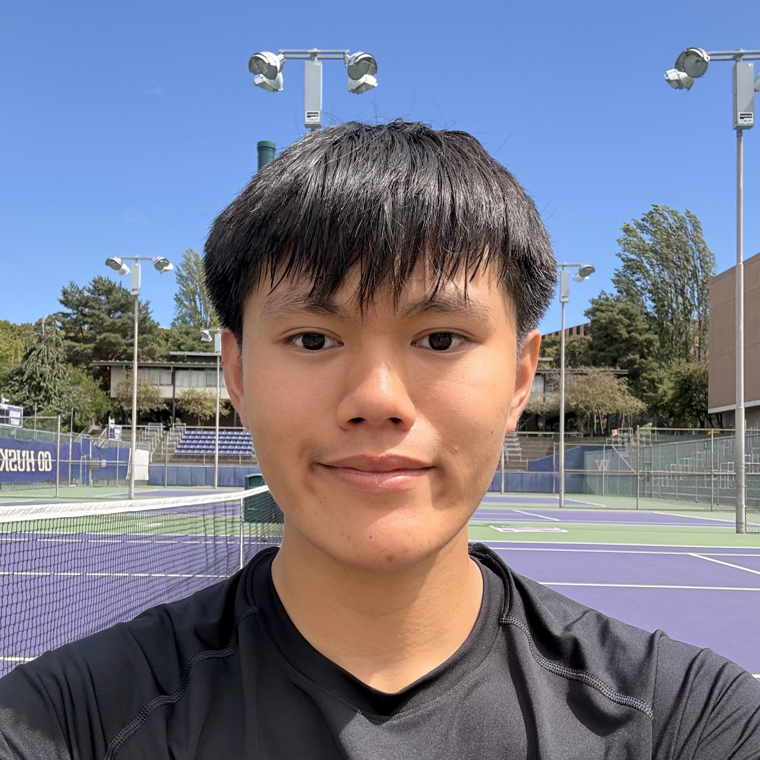 Jackson Le smiling in front of a tennis court.