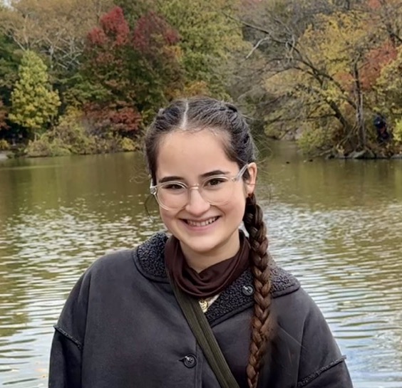 Kate Sestero smiling in front of a body of water and trees.