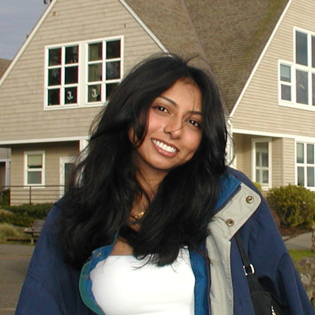 Syreeta Das smiling in front of a beige house.
